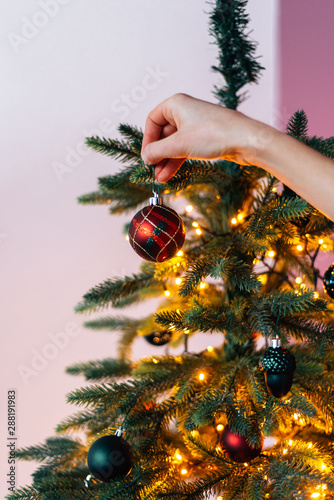 Crop hand hanging bauble on Christmas tree
