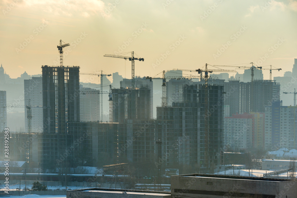 Obraz premium Constraction site with industrial cranes in city at sunset