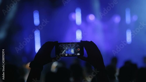 4k Rreal live streaming in disco hall during party light show laser lights show time.Silhouette hands of audience  taking photo with mobile phone. Recording Video in party. Shooted on Red Epic Dragon. photo