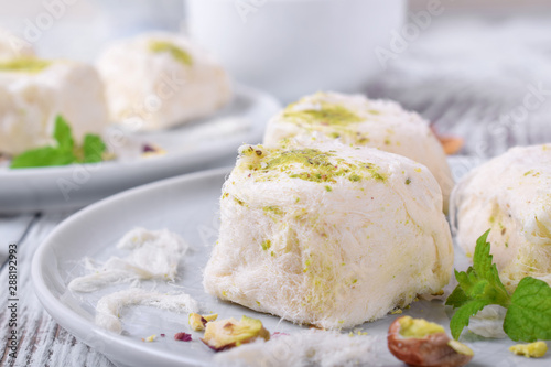 Cotton candy with pistachio on ceramic plate on white wooden table