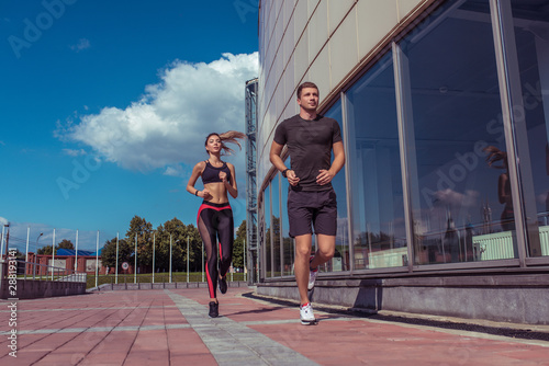 Athletic couple man and girl in summer city, run on morning run, burning calories, cardio fitness training day and morning. Healthy lifestyle style. Sportswear, friends and relationships are paired.