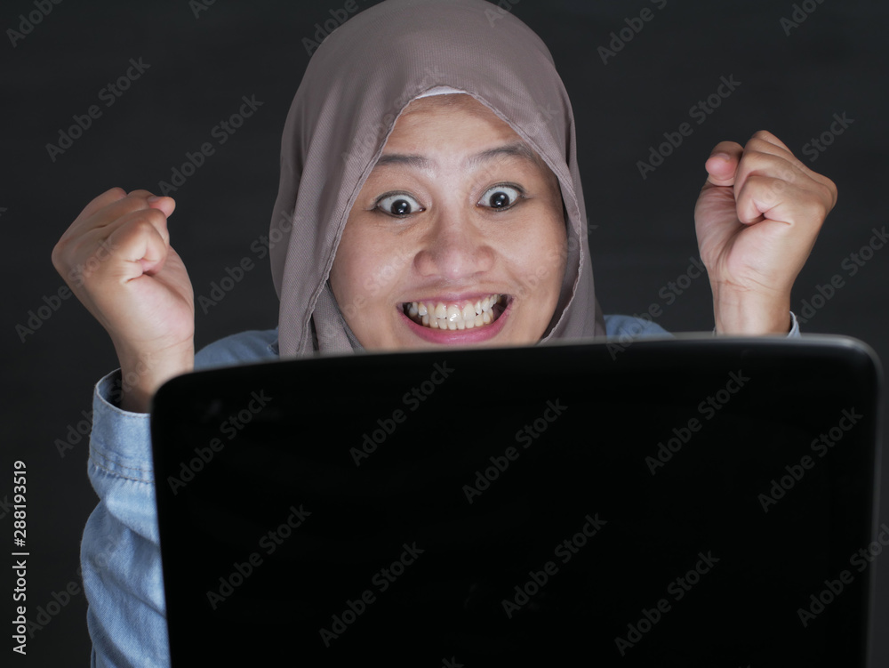 Muslim Lady Using Laptop Shows Winning Gesture, Receiving Good News on Her Email Muslim Lady Using Laptop Shows Winning Gesture, Receiving Good News on Her Email