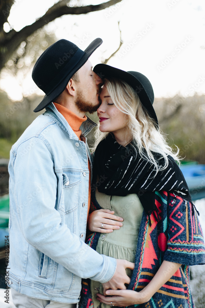 Couple kissing on pier near trees and boats on water