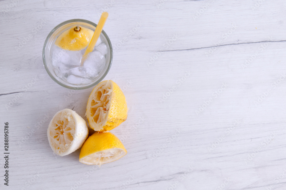 Glass of water with lemon and squeezed lemons on a wooden table. Glass of water with lemon and squeezed lemons on a wooden table.
