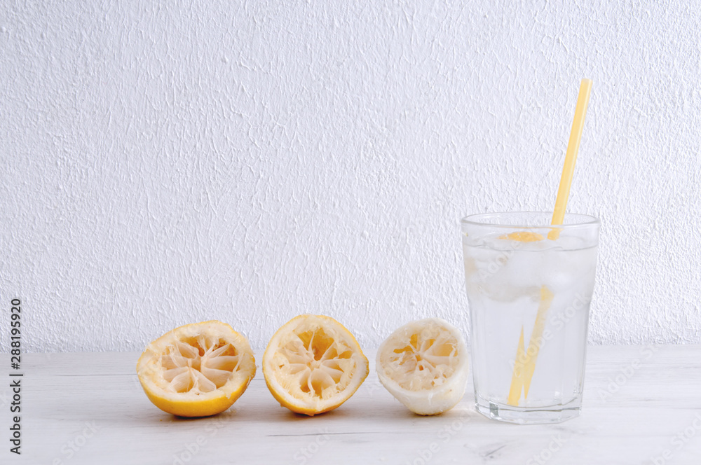 Glass of water with lemon and squeezed lemons on a wooden table. Glass of water with lemon and squeezed lemons on a wooden table.