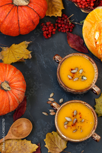 Pumpkin soup in two bowls on a dark background  Autumn composition  vertical orientation  top view