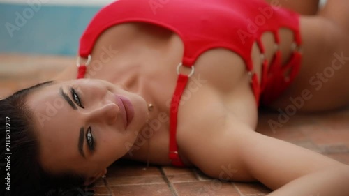 Sexy seductive attractive woman posing in red swimsuit near swimming pool