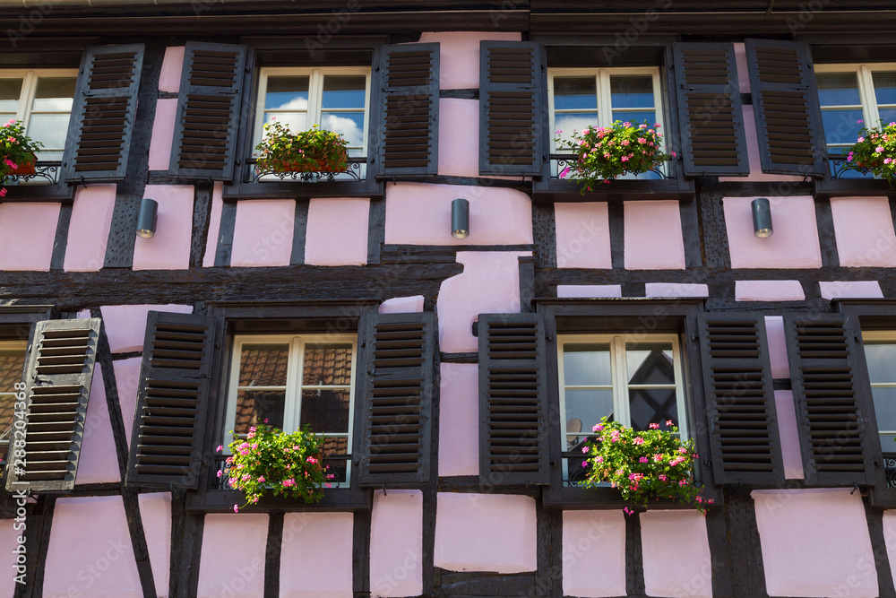 Fototapeta premium Colorful wall of old half-timbered house with multiple windows and wooden shutters