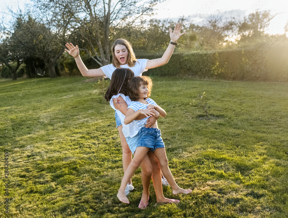 Little sisters playing in the garden on a summer sunset Little sisters playing in the garden on a summer sunset