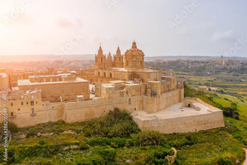 St. Paul's Cathedral in the town of Mdina surrounded by a fortress narrow streets, aerial view.