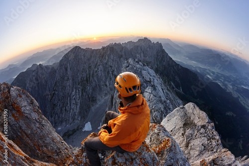 Climber with orange helmet sitting on Ellmauer Halt at sunrise, Wilder Kaiser, Ellmauer Halt, Tyrol, Austria photo