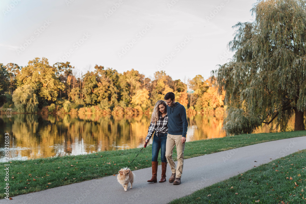 A couple in their twenties walking their dog on an autumn day A couple in their twenties walking their dog on an autumn day