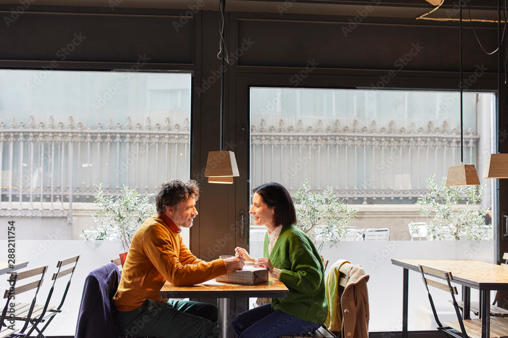 Couple With Present Sitting At Table In Restaurant Couple With Present Sitting At Table In Restaurant