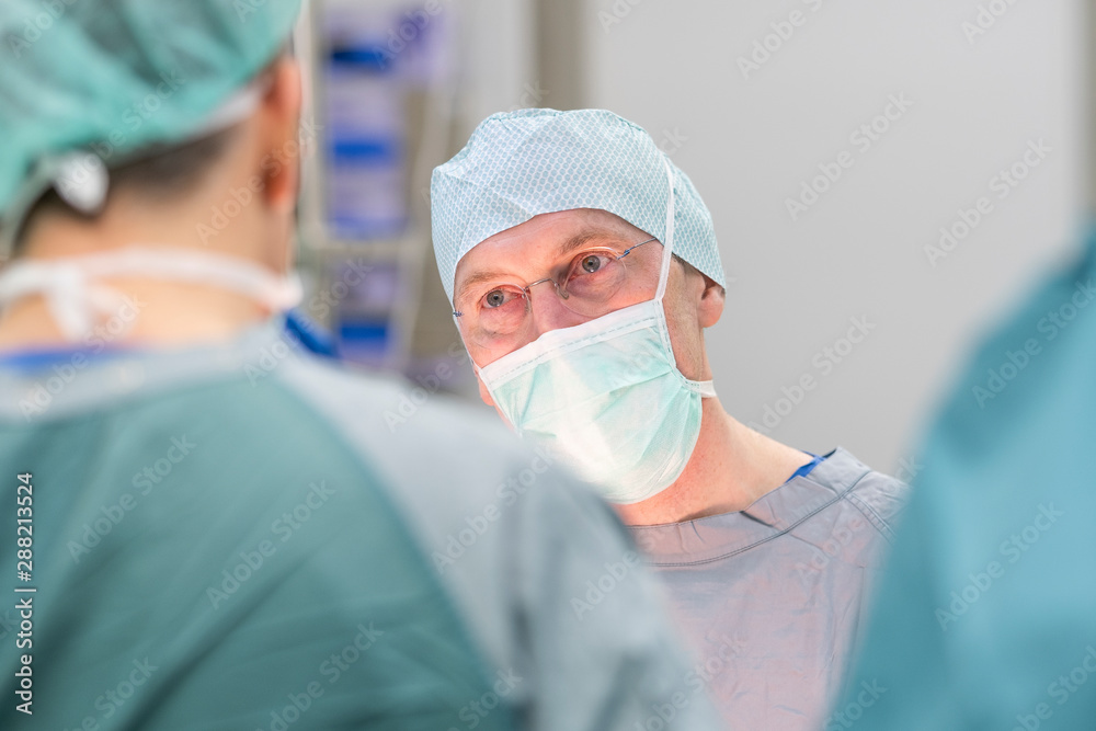 Surgeon during surgery, looking to colleague Surgeon during surgery, looking to colleague
