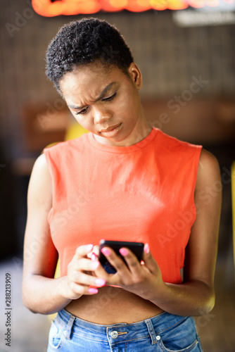 Portrait of skeptical young woman looking at cell phone