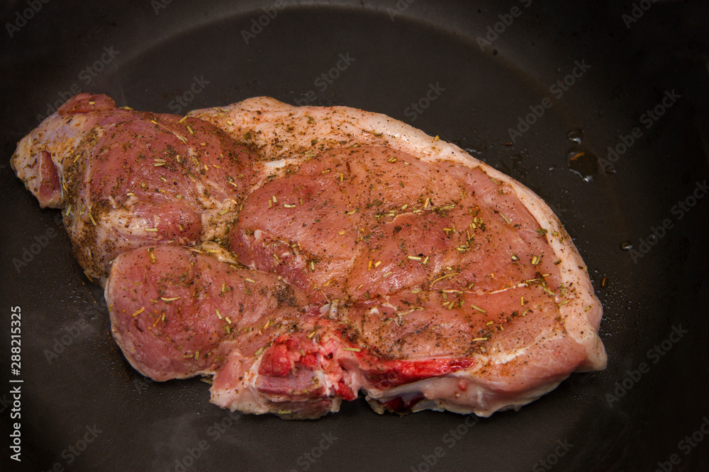 Fresh raw pork steak with spices roasting on frying pan Fresh raw pork steak with spices roasting on frying pan