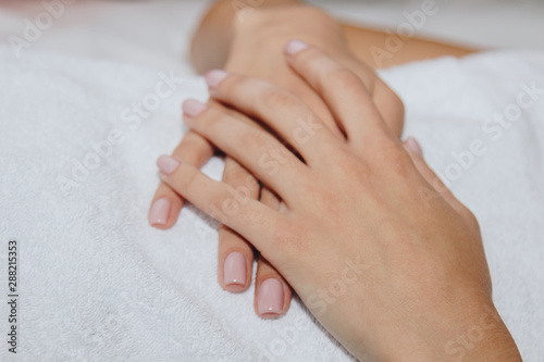close-up female hands lie on a white terry towel. preparation for spa treatments