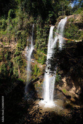View of a high waterfall with sunlight and surrounded by rainforest