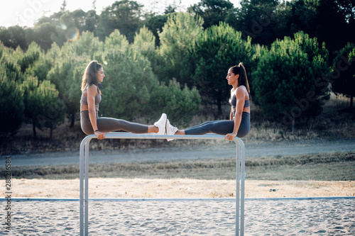 Two twin sisters exercising on parallel bars photo