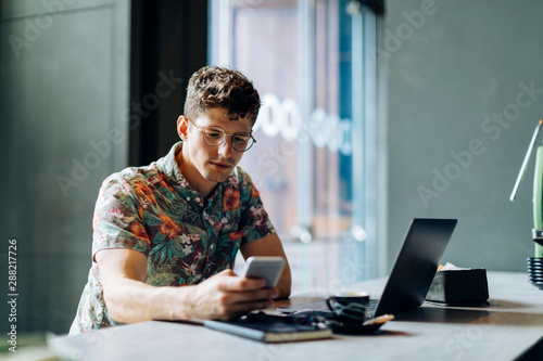 Young man using smartphone while sitting in cafe photo