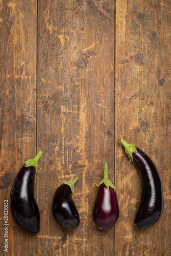 Freshly picked raw eggplants on dark rustic wooden background