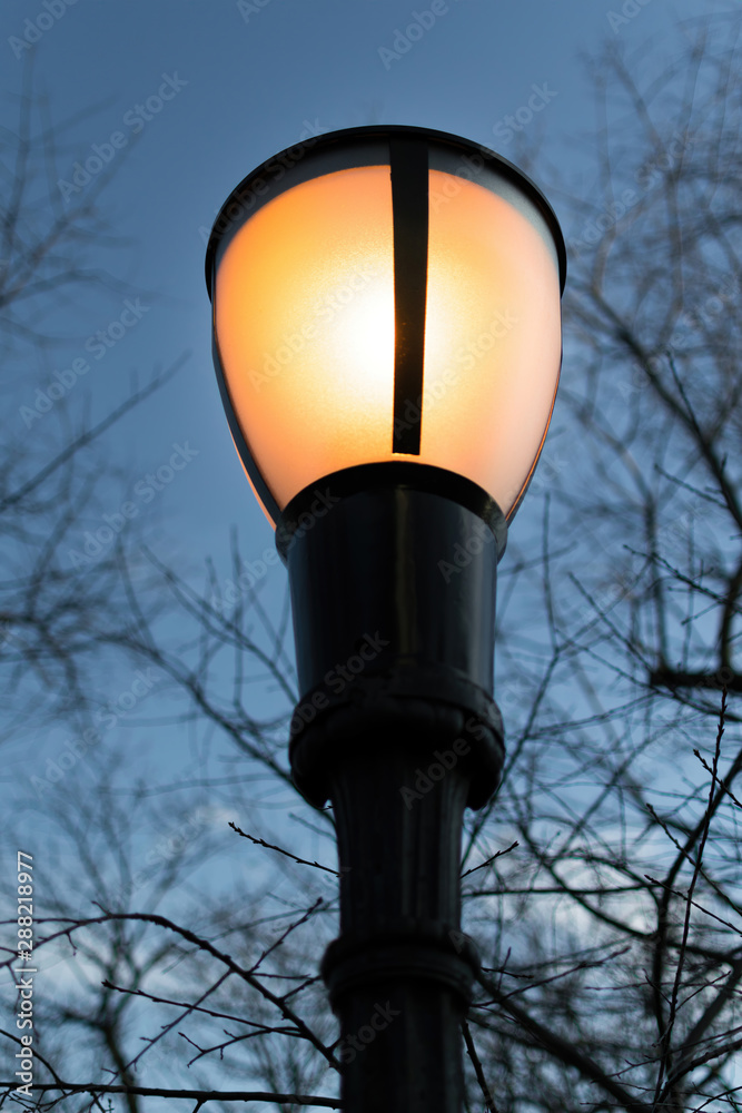 Glowing yellow street lantern, against a blue evening sky Glowing yellow street lantern, against a blue evening sky