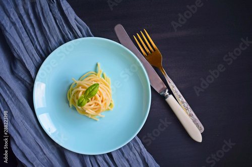 Delicious spaghetti with greens on a black background.