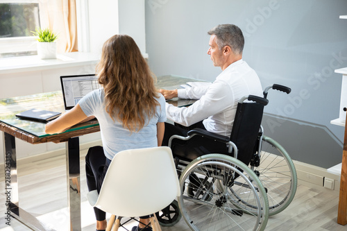 Disabled Businessman Sitting With His Partner In Office
