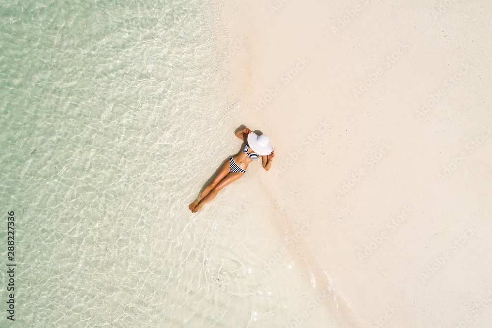 Summer holiday fashion concept - tanning girl wearing sun hat at the beach  on a white sand