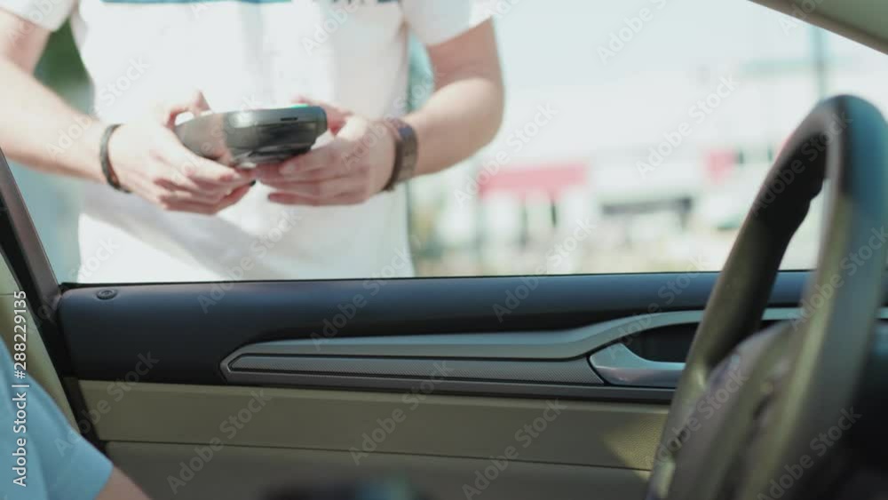 Man making payment transaction with his mobile phone at car buy coffee finance money banking business electronic terminal connection customer device financial modern slow motion Man making payment transaction with his mobile phone at car buy coffee finance money banking business electronic terminal connection customer device financial modern slow motion