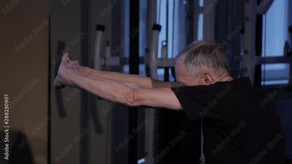 A man of the age performs joint gymnastics for the elbows and back in