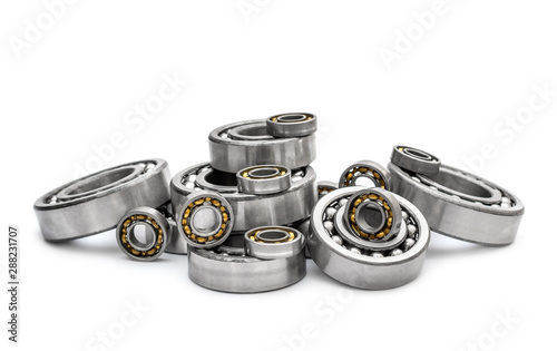 Heap of different metal bearings on white.