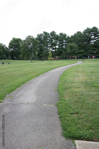 Pathway going thru park with trees in background