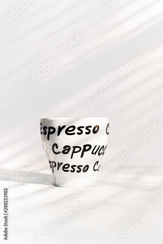 Single ceramic coffee cup, hand written words, with ethereal light and shadows