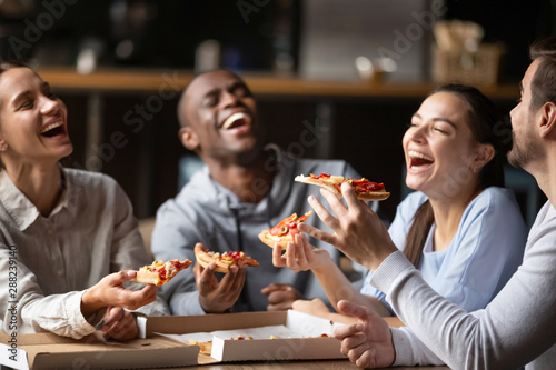Diverse friends eating pizza and having fun together in cafe photo