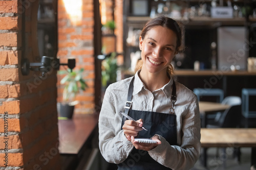 Head shot portrait of smiling waitress ready to take customer order photo