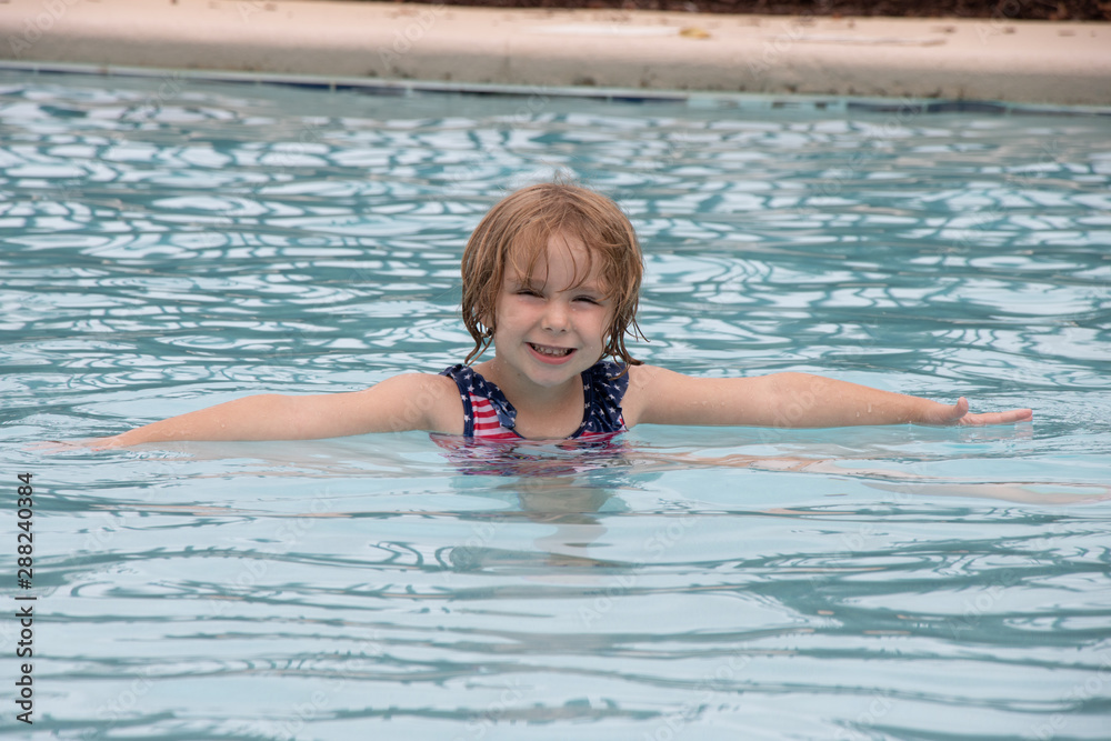 Little girl smiling while playing in swimming pool