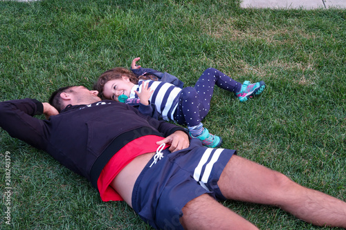 man and little girl laying on grassing laughing and smiling at each other