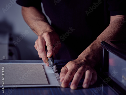Worker cutting sheet with stationery knife on surface photo
