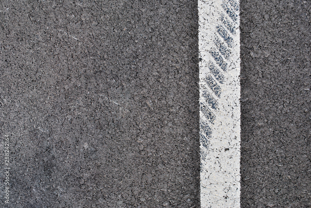 Fototapeta premium Asphalt texture with white line and tire marks . Top view