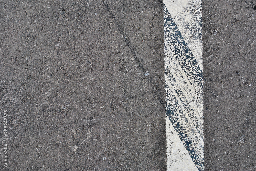 Fototapeta premium Asphalt texture with white line and tire marks . Top view