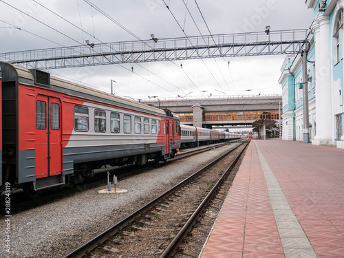 The passenger train at the railway station on a cloudy day. Electric train, wagons, railway platform.