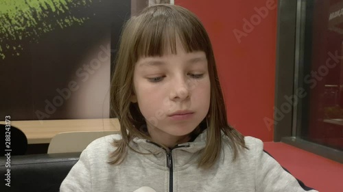 A teenage girl eats French fries for dinner at a fast food cafe.