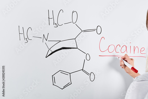 cropped view of woman writing cocaine on white board