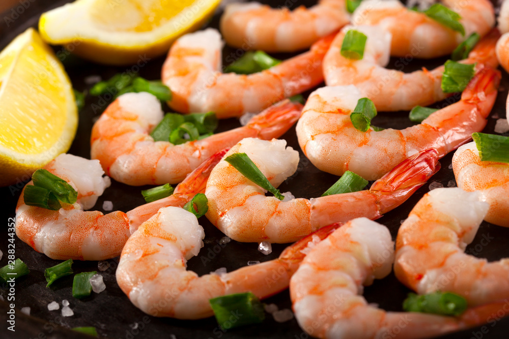 Prawns Shrimps roasted on pan with lemon, garlic and herbs on black background. Prawns Shrimps roasted on pan with lemon, garlic and herbs on black background.