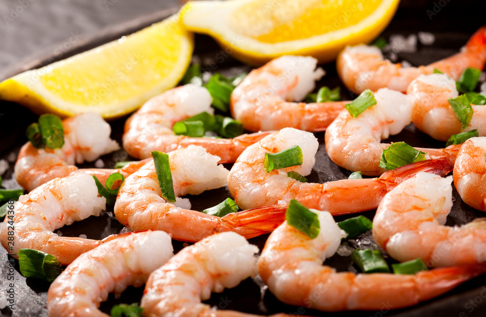 Prawns Shrimps roasted on pan with lemon, garlic and herbs on black background. Prawns Shrimps roasted on pan with lemon, garlic and herbs on black background.
