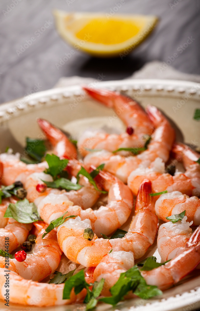 Prawns Shrimps on a plate with lemon, garlic and herbs on black background. Prawns Shrimps on a plate with lemon, garlic and herbs on black background.