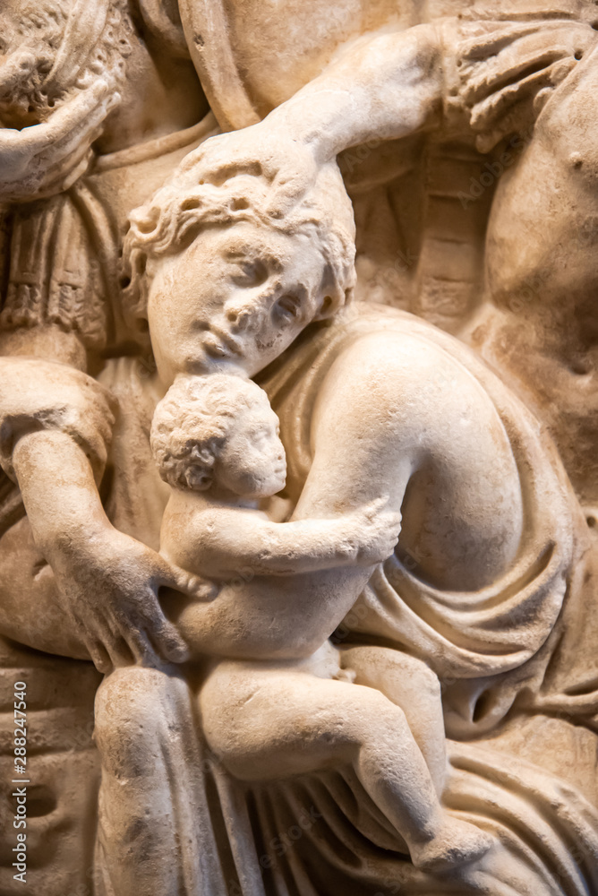 Detail of ancient engraved sculpture on marble showing woman protecting child Detail of ancient engraved sculpture on marble showing woman protecting child