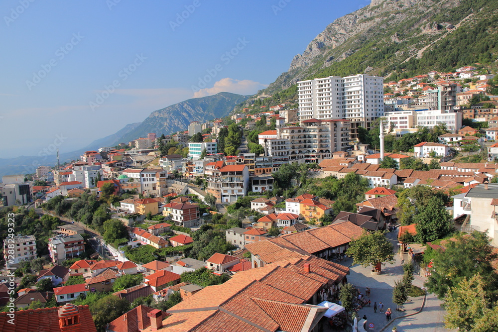 Panorama of the city of Kruja in central Albania from the hill with a medieval citadel overlooking modern residential buildings against the backdrop of the mountains.