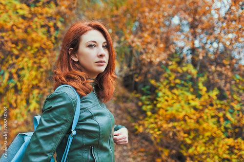 Young woman with autumn tree. A girl walks in cold autumn among the trees in a beautiful forest.